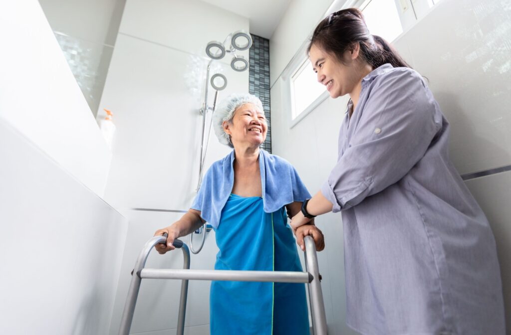 A caregiver helping a happy senior get ready for a shower.