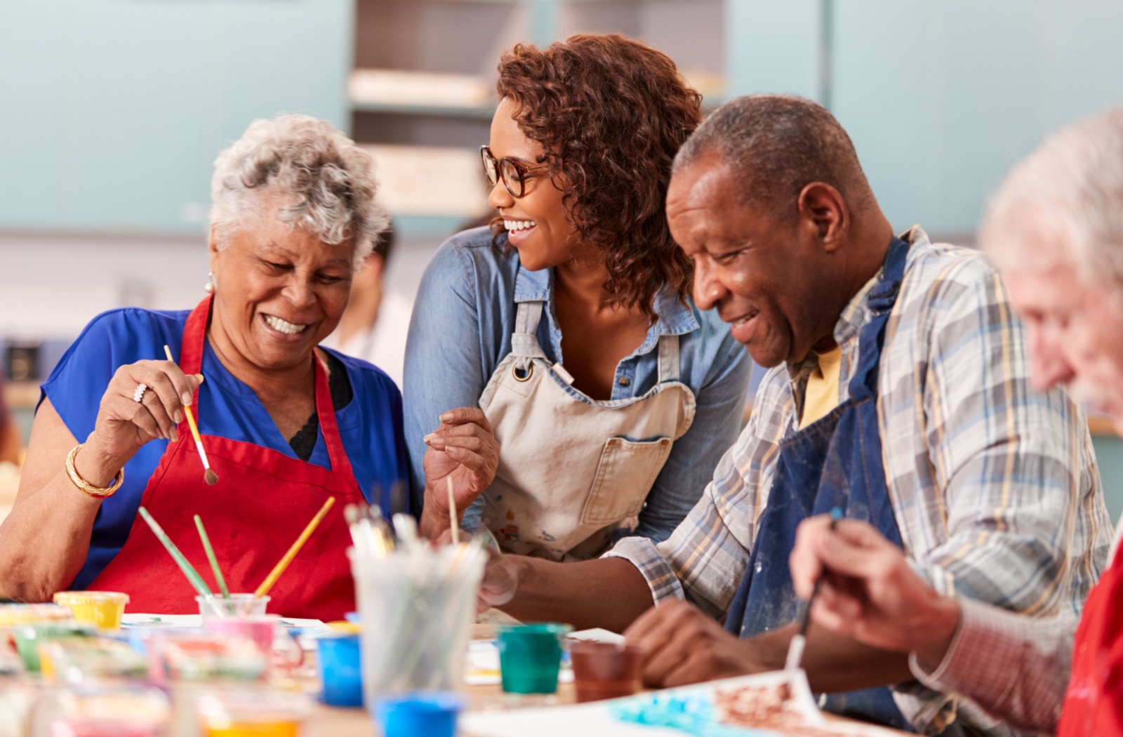 A group of older adults smiling and having fun while doing a painting class in independent living.
