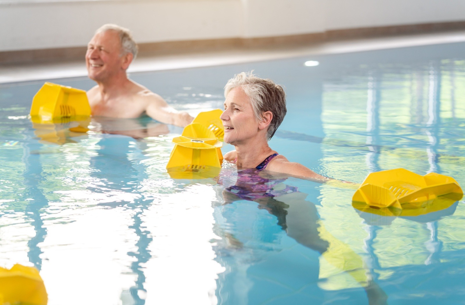 Two seniors practice aquatic therapy in a pool
