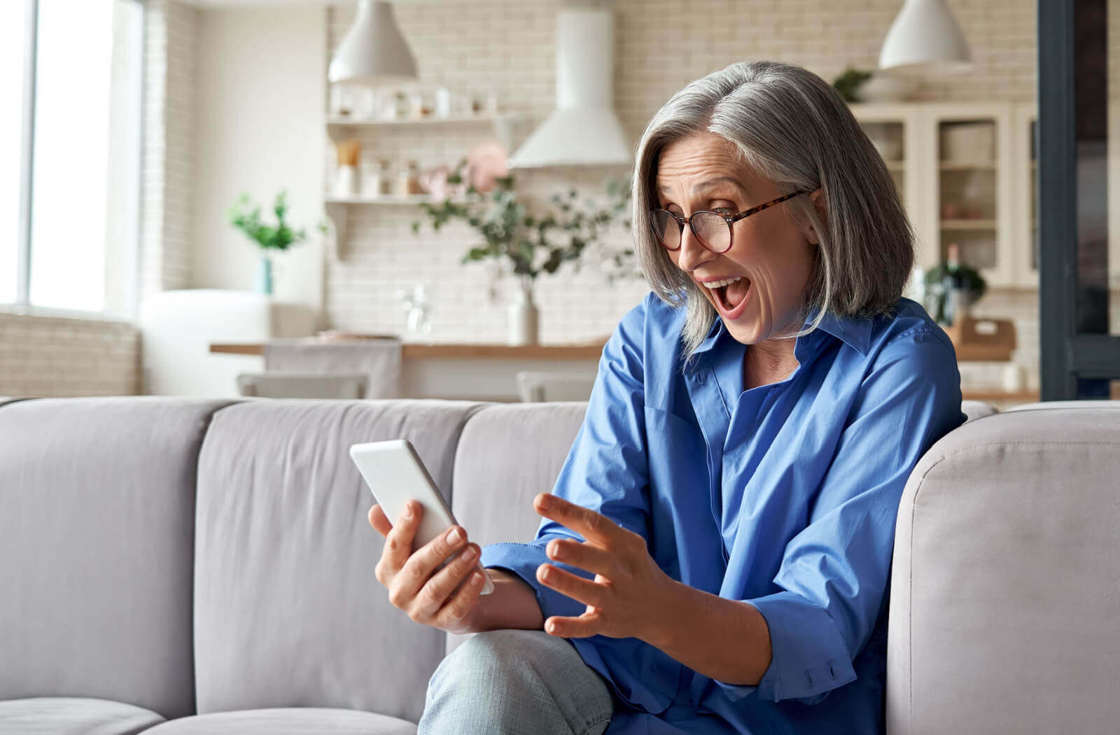 An older adult in senior living celebrating after checking trivia answers on their phone.