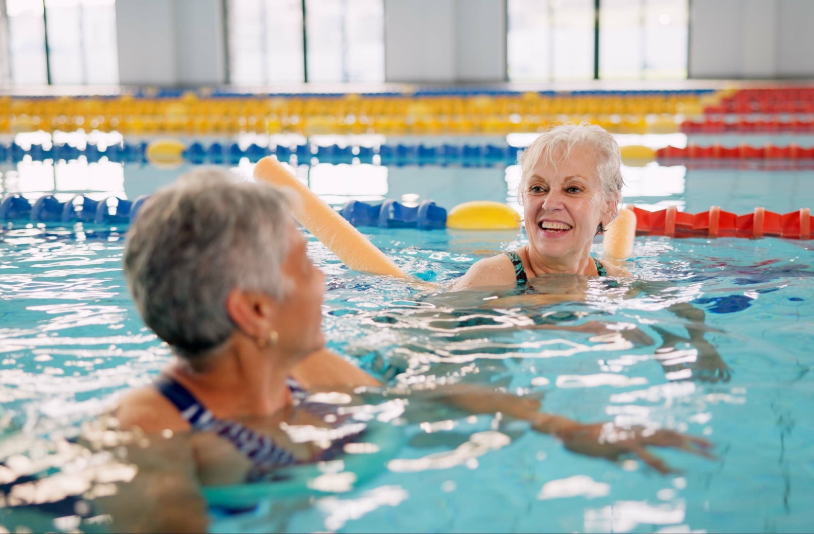 Two senior friends enjoy a swim in the community pool